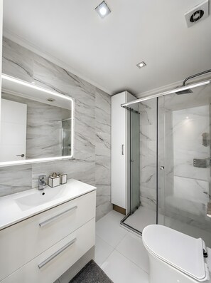 A modern bathroom with a marble backsplash, a large mirror, a glass-enclosed shower, and a white sink. - Beachfront, 12th Floor with Stunning Views, Maite 2, Benalmádena (Benalmádena)
