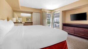 Una habitación de hotel con una cama grande, televisión, cómoda y ventana con cortinas.