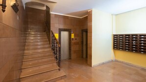 A staircase with a wooden handrail, a wall-mounted mailbox, and a door leading to an elevator. - Goito 3 (Bologna)