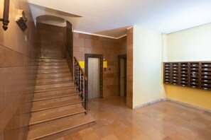 Eine Treppe mit Holzhandlauf, einem an der Wand befestigten Briefkasten und einer Tür zum Aufzug.