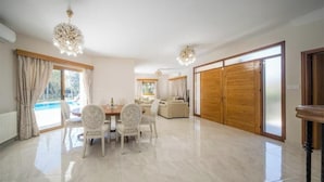 Uma sala de estar ampla com uma mesa de jantar, cadeiras e uma grande porta deslizante.