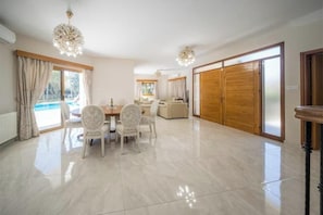 Amplia sala de estar con una mesa de comedor, sillas y un gran ventanal corredero.