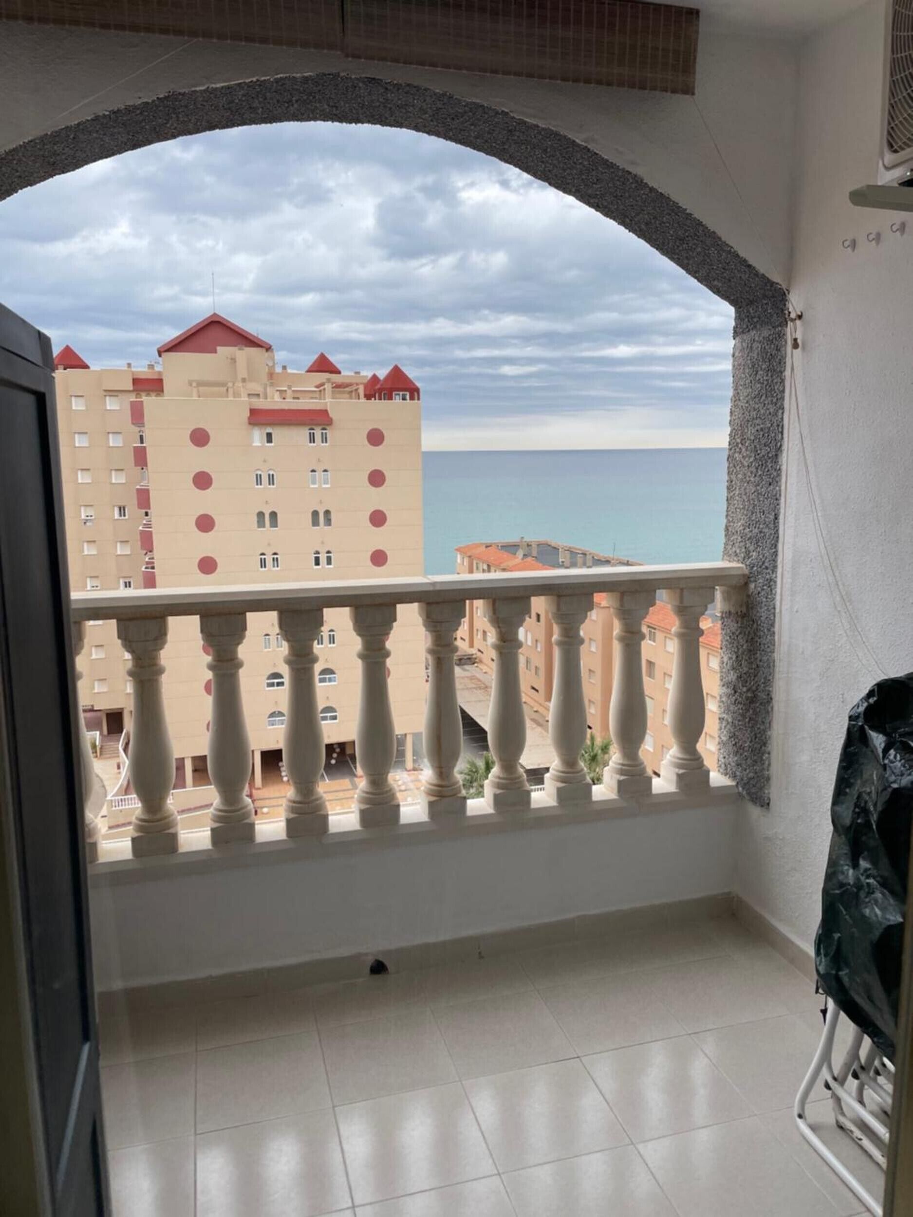 Un balcon avec vue sur un immeuble et la mer.