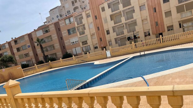 A swimming pool with a yellow balustrade, surrounded by multi-story residential buildings.