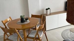 A dining area with a round wooden table, four wooden chairs, and a small potted plant on the table.