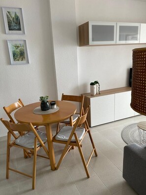 Un comedor con una mesa redonda de madera, cuatro sillas de madera y una pequeña planta en maceta sobre la mesa.