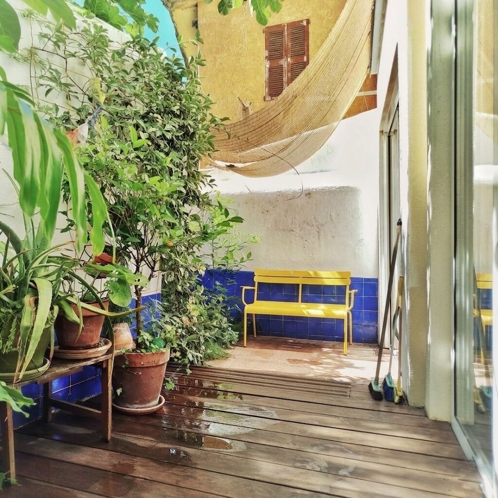 Eine Holzterrasse mit Kübelpflanzen, einer Hängematte, einer Bank und einer gefliesten Wand.