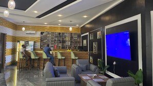 A modern bar area with seating, a television, and a wine rack. - Golden Tulip Hotel Onitsha (Onitsha)