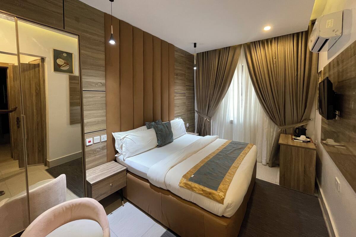 Une chambre d’hôtel moderne équipée d’un grand lit, d’une table de chevet, d’une chaise, d’une armoire et d’un téléviseur.