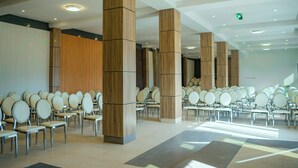 A spacious hall with rows of chairs and large wooden pillars, likely a conference or event space.