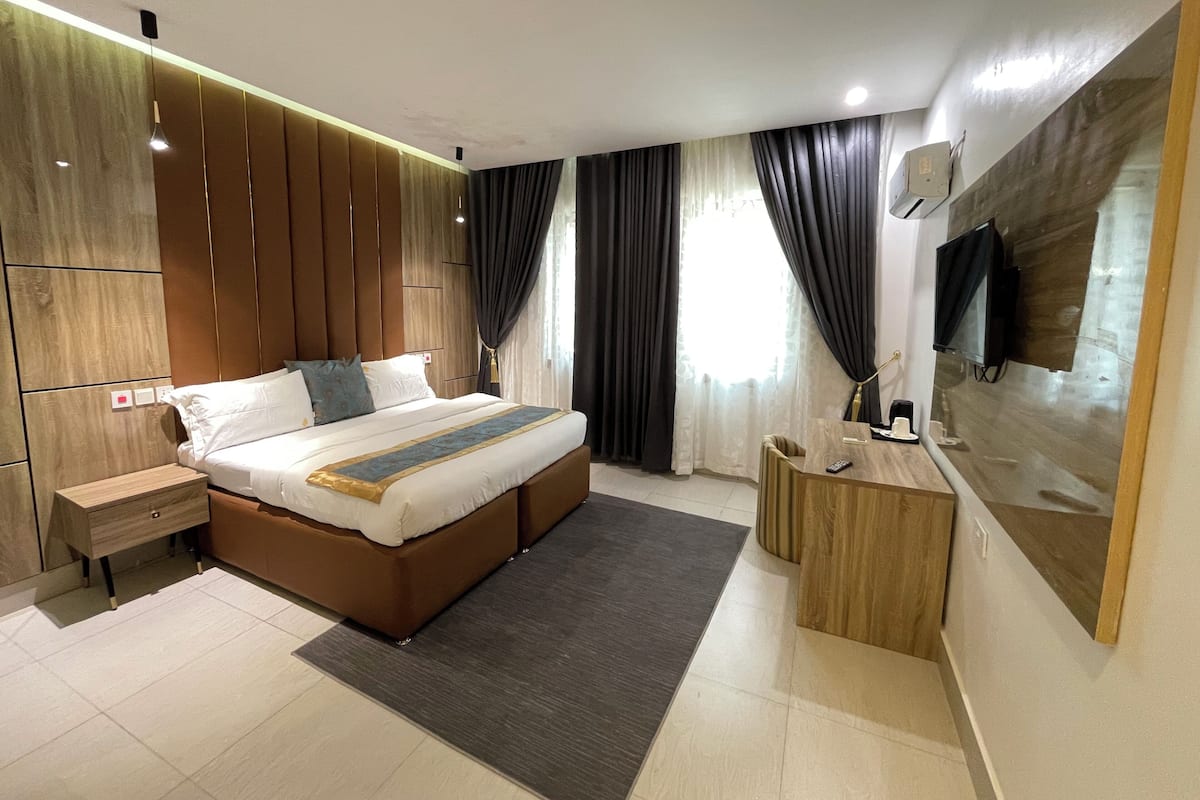 Une chambre moderne avec un grand lit, des tables de chevet, un bureau et un téléviseur fixé au mur.