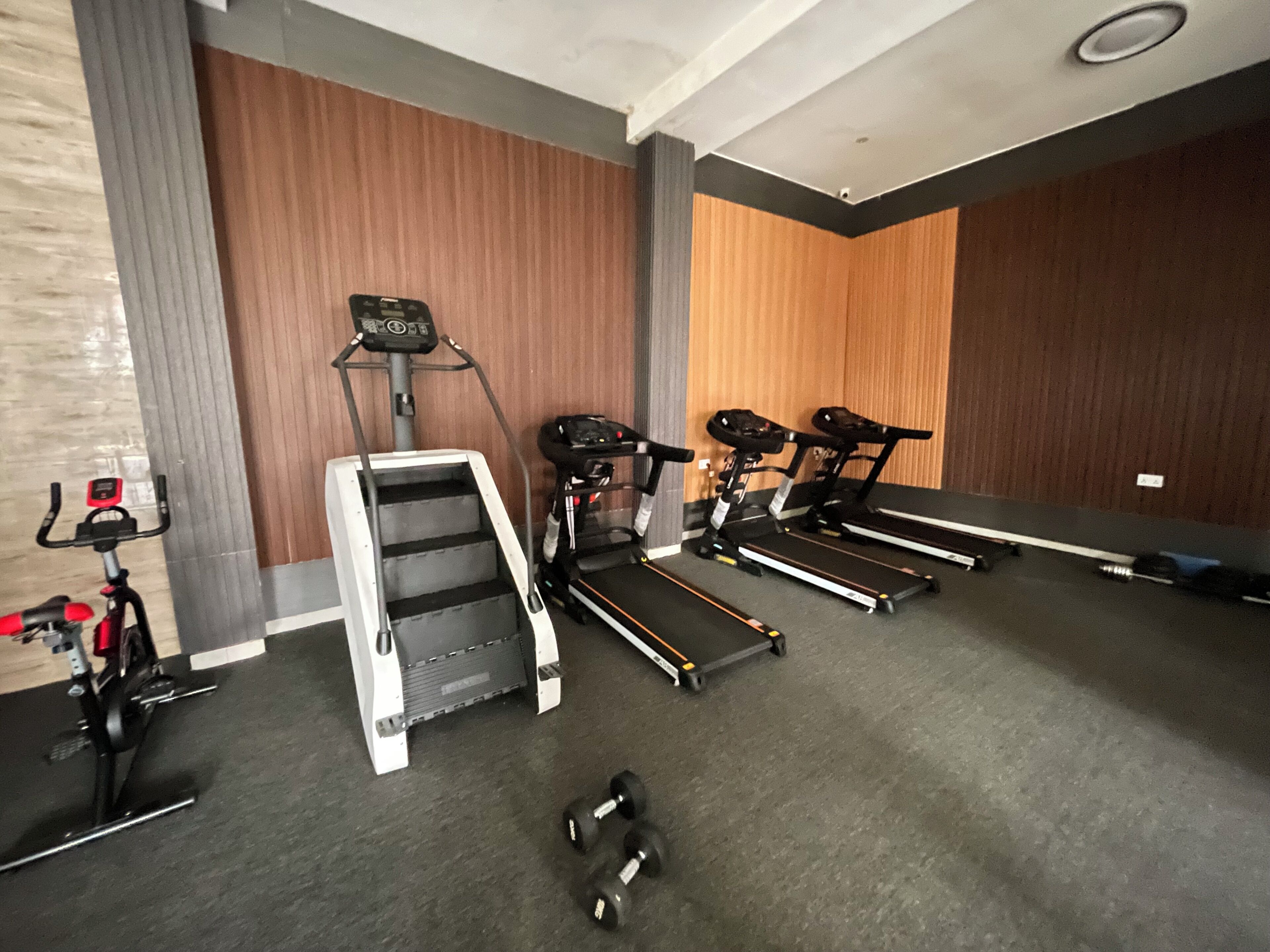 A gym with treadmills, a stair climber, and dumbbells.