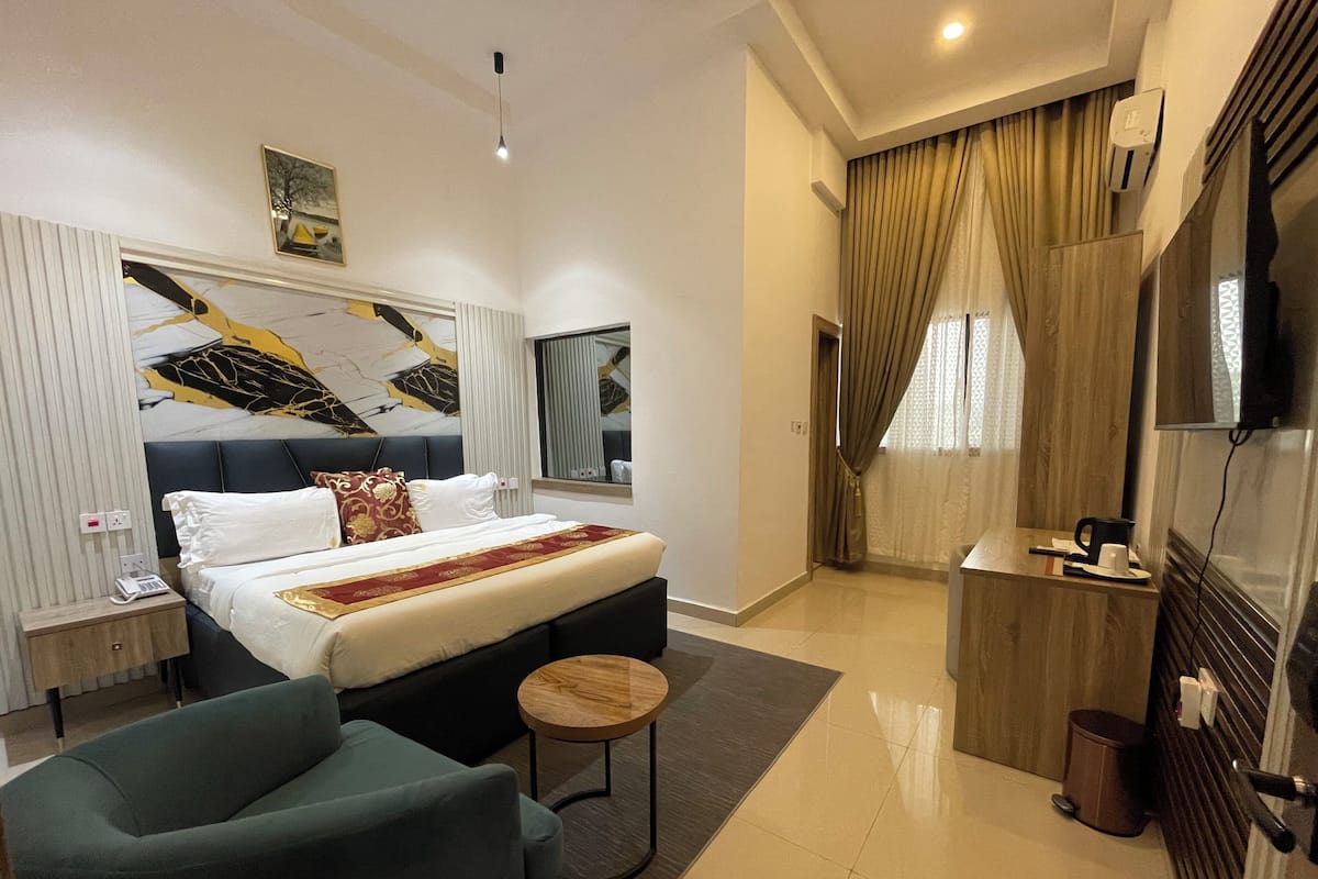Une chambre d’hôtel moderne équipée d’un lit, d’un coin salon, d’une petite table, d’une télévision et d’une salle de bain.