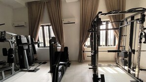 A gym with exercise equipment, large windows, and curtains.