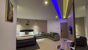 A modern hotel room with a bed, sofa, desk, and a TV. - Golden Tulip Hotel Onitsha (Onitsha)