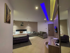 Una habitación de hotel moderna con cama, sofá, escritorio y televisión.