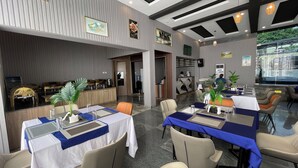 A modern restaurant with a bar area, tables with blue tablecloths, and a reception desk. - Golden Tulip Hotel Onitsha (Onitsha)