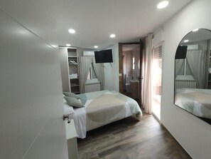 Un dormitorio con cama, televisor, armario y espejo.