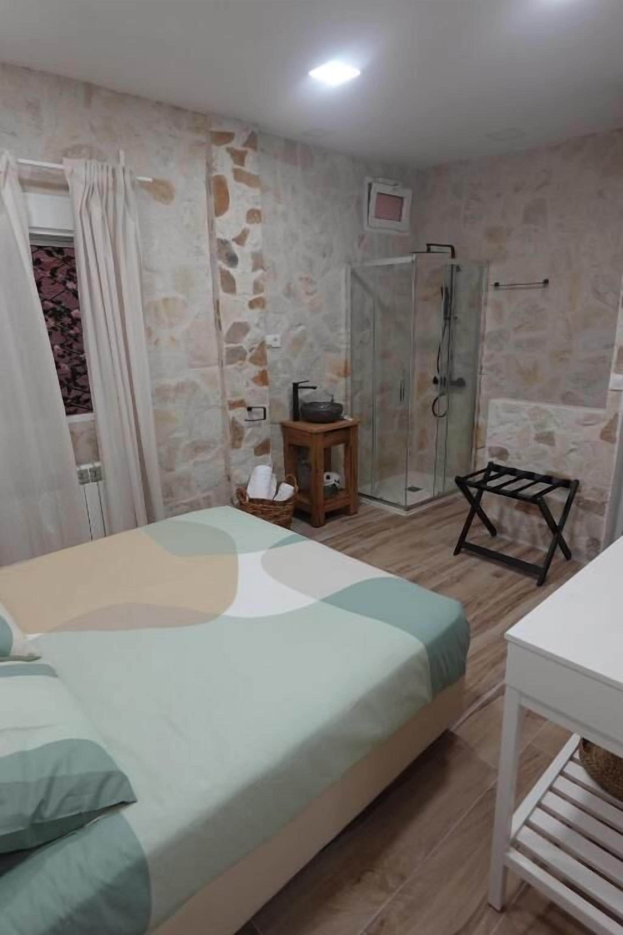 Un dormitorio con cama, una mesita, ducha y un armario blanco.