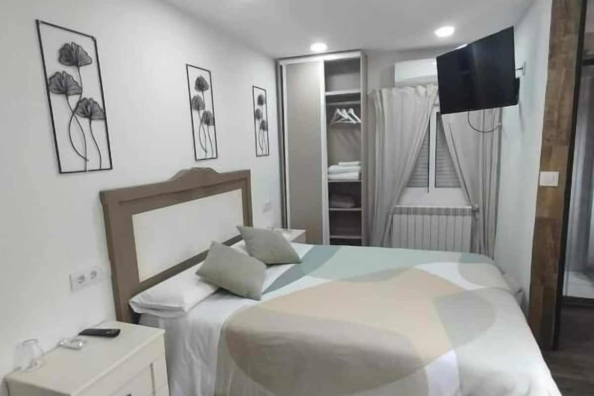 Un dormitorio con cama, mesita de noche y armario.