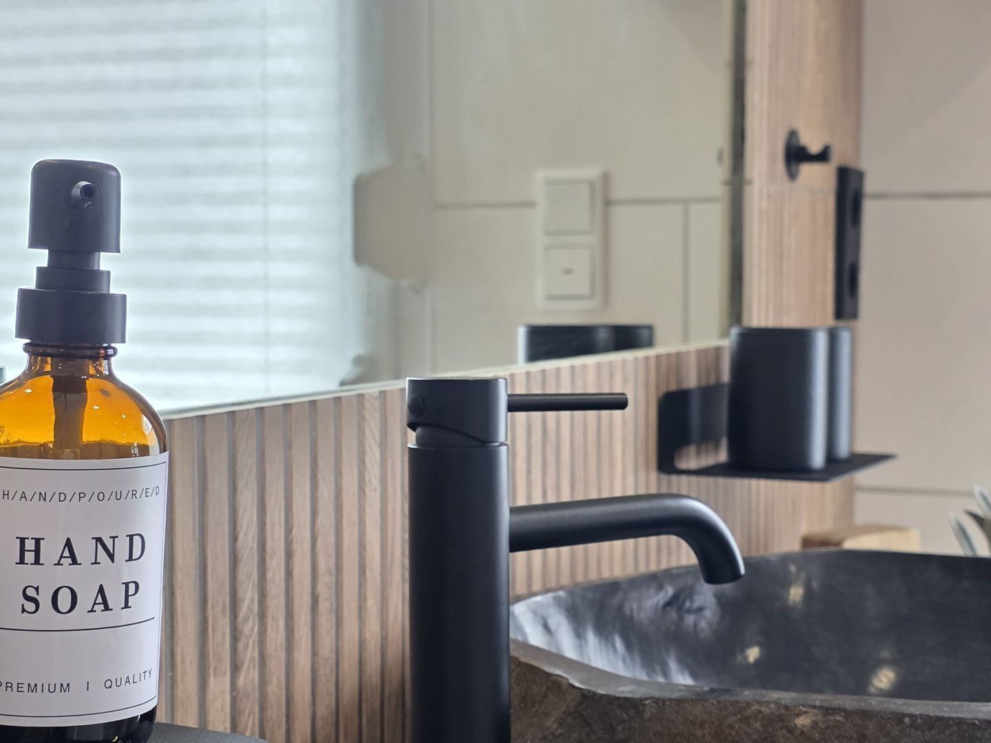 Een fles handzeep op een aanrecht met een modern badkamermeubel en spiegel.