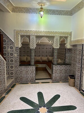 A room with intricate tile patterns, a central seating area with cushions, and a patterned floor design. - Entire apartment, in the medina, rooftop, 7-minute walk from the Oudayas and the beaches. (Rabat)