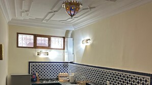 A kitchen with a tiled backsplash, a stove, a refrigerator, and a ceiling fan. - Entire apartment, in the medina, rooftop, 7-minute walk from the Oudayas and the beaches. (Rabat)