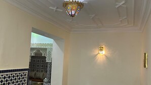 A dining area with a round table, chairs, a chandelier, and a patterned wall. - Entire apartment, in the medina, rooftop, 7-minute walk from the Oudayas and the beaches. (Rabat)