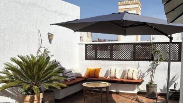 A patio with a seating area, a potted plant, and a view of a tower. - Entire apartment, in the medina, rooftop, 7-minute walk from the Oudayas and the beaches. (Rabat)
