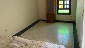 A room with a bed, a window with a geometric pattern, and an air conditioning unit on the wall. - Entire apartment, in the medina, rooftop, 7-minute walk from the Oudayas and the beaches. (Rabat)