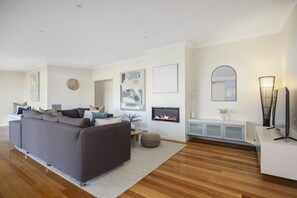 Ein modernes Wohnzimmer mit grauem Sofa, Kamin, Flachbildfernseher und minimalistischem Design.