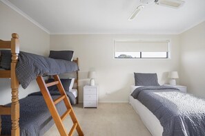 Ein Schlafzimmer mit Etagenbetten, einer Himmelsleiter, Nachttischen und einem Fenster.