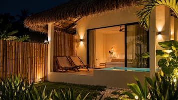A modern villa with a thatched roof, a pool, and a well-lit interior.