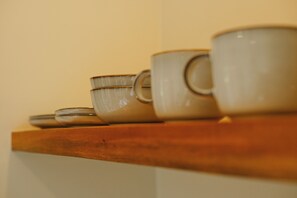 A row of ceramic cups and bowls on a wooden shelf. - SIROCO VILLAS (San Juan)