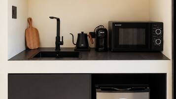 A compact kitchen with a microwave, coffee maker, and a refrigerator.
