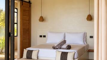 A bedroom with a large bed, a ceiling fan, and a view through a glass door.