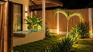 A modern house with a thatched roof, a swimming pool, and a bamboo fence.