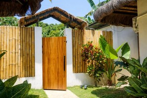 A wooden gate with a white wall and a thatched roof structure above it. - SIROCO VILLAS (San Juan)