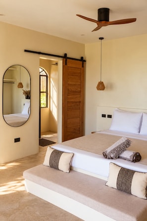 A bedroom with a bed, a ceiling fan, a large mirror, and a sliding door. - SIROCO VILLAS (San Juan)