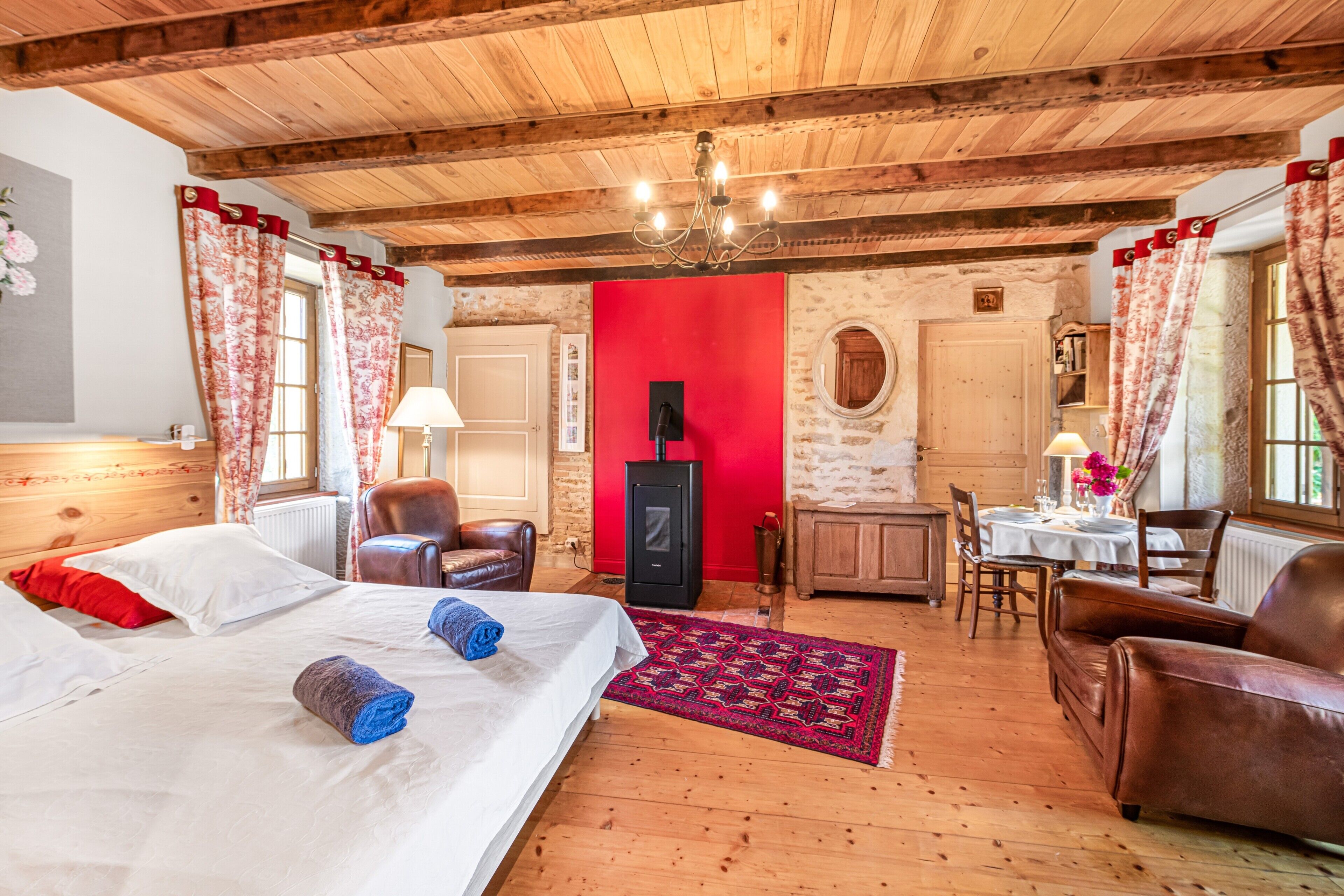 Una habitación con piso de madera, una cama, un escritorio y un comedor.