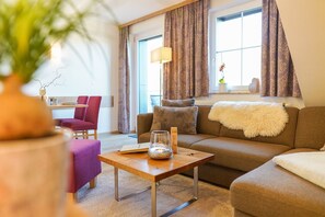 A living room with a sofa, a coffee table, a chair, and a lamp. - Simon's Vacation Rental 7 - Stylish, modern, and with a magnificent view (Oberwiesenthal)