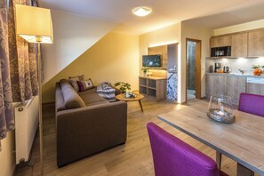 A modern living room with a sofa, a coffee table, and a dining table with chairs. - Simon's Vacation Rental 7 - Stylish, modern, and with a magnificent view (Oberwiesenthal)