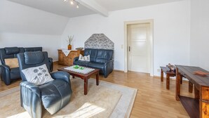 Un salón amplio con sofás de cuero, una mesa de centro de madera y una pared decorativa de piedra.