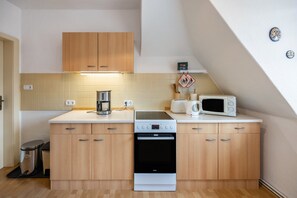 Une cuisine compacte dotée de meubles en bois, d’une machine à café, d’un four à micro-ondes et d’une cuisinière.
