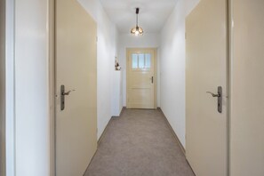 A hallway with carpeted floors, beige walls, and two doors on either side.