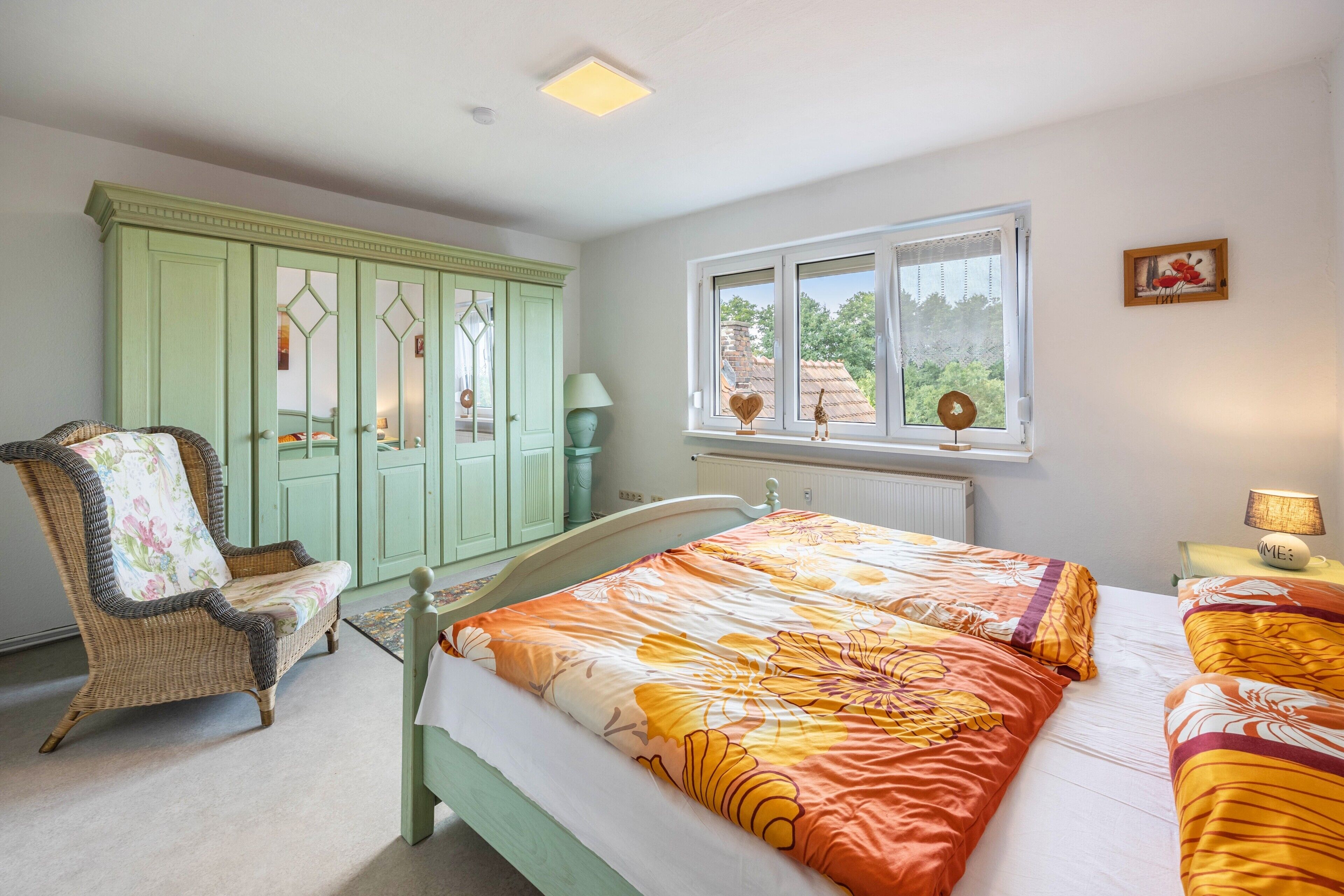 Un dormitorio con cama, una silla, un armario y una ventana con vistas.