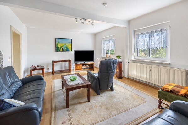 A modern living room with a sofa, a coffee table, a TV, and a window with curtains.