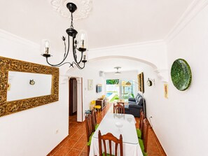 A dining area with a long table, chairs, and a chandelier.