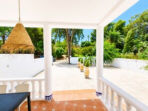A covered outdoor area with a white railing, a hanging light fixture, and potted plants.