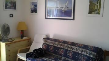 Una habitación con sofá, escritorio, lámpara y decoración en la pared.